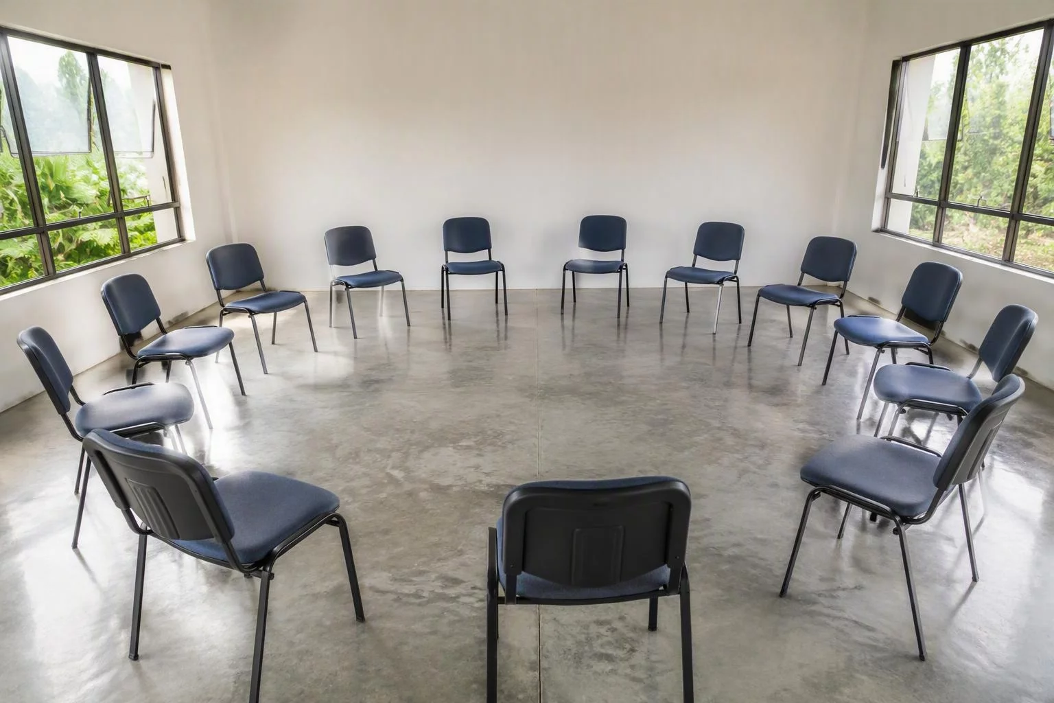 Cadeiras vazias dispostas em círculo em uma sala clara de reunião